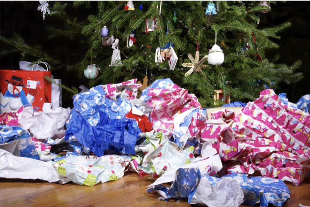 A Christmas tree surrounded by discarded wrapping paper, 
symbolizing the environmental and societal toll of holiday excess. Courtesy of PHS WasteKit.